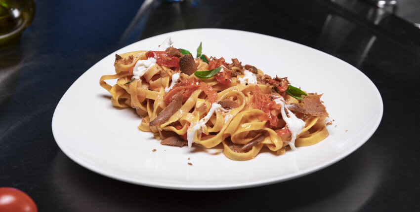 Plate of Egg Fettuccine with cherry tomatoes, burrata